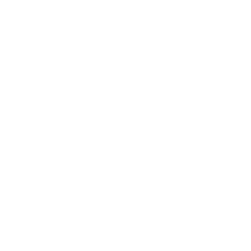 Una persona con un abrigo negro y una bufanda roja camina por un parque cubierto de nieve, pasando junto a los bancos a lo largo de un sendero.