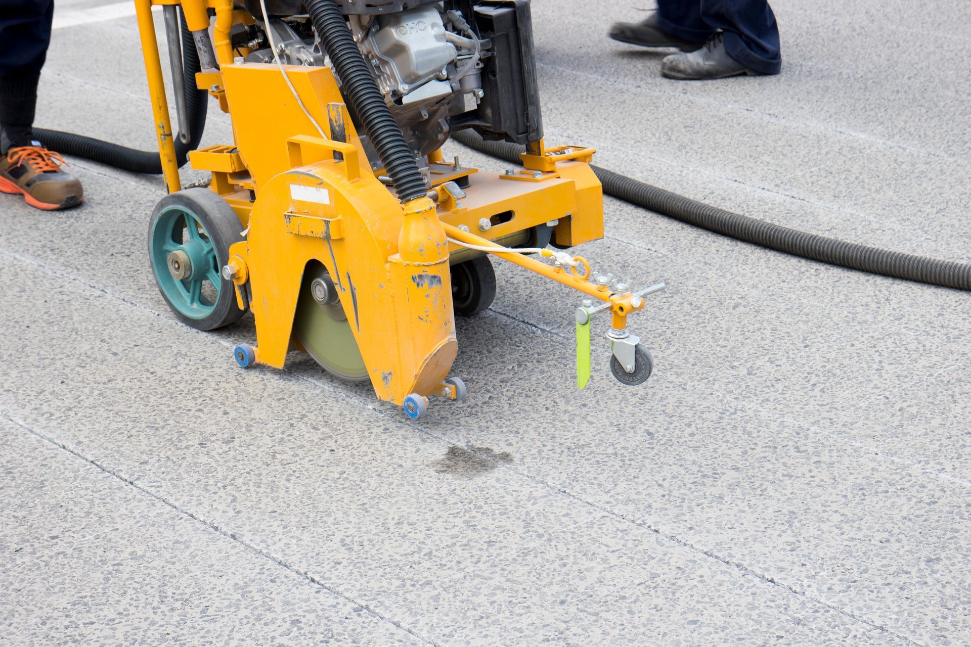 Scie à béton jaune traçant des rainures dans l'asphalte.
