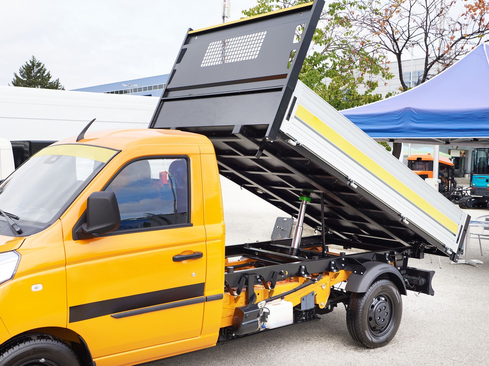 Camion-benne jaune, benne levée, à l'extérieur.