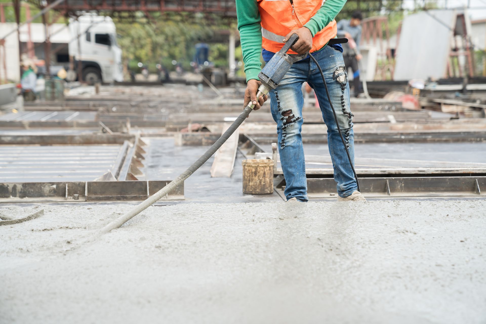 Un ouvrier du bâtiment utilise un vibrateur pour niveler le béton frais sur un chantier.