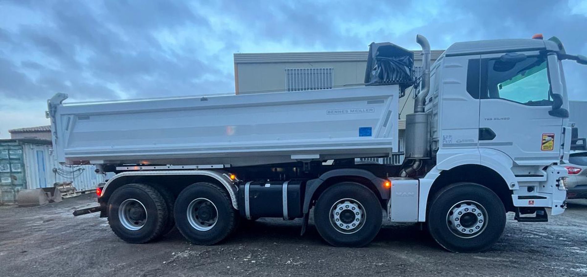 Camion-benne blanc stationné par temps nuageux.