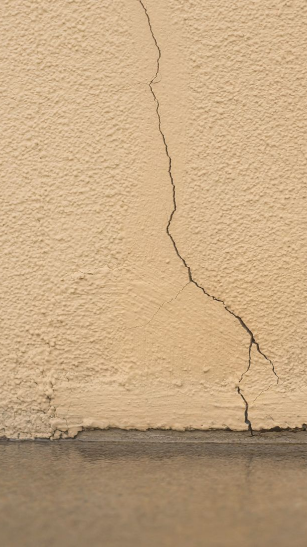 Fissure verticale dans un mur beige extérieur