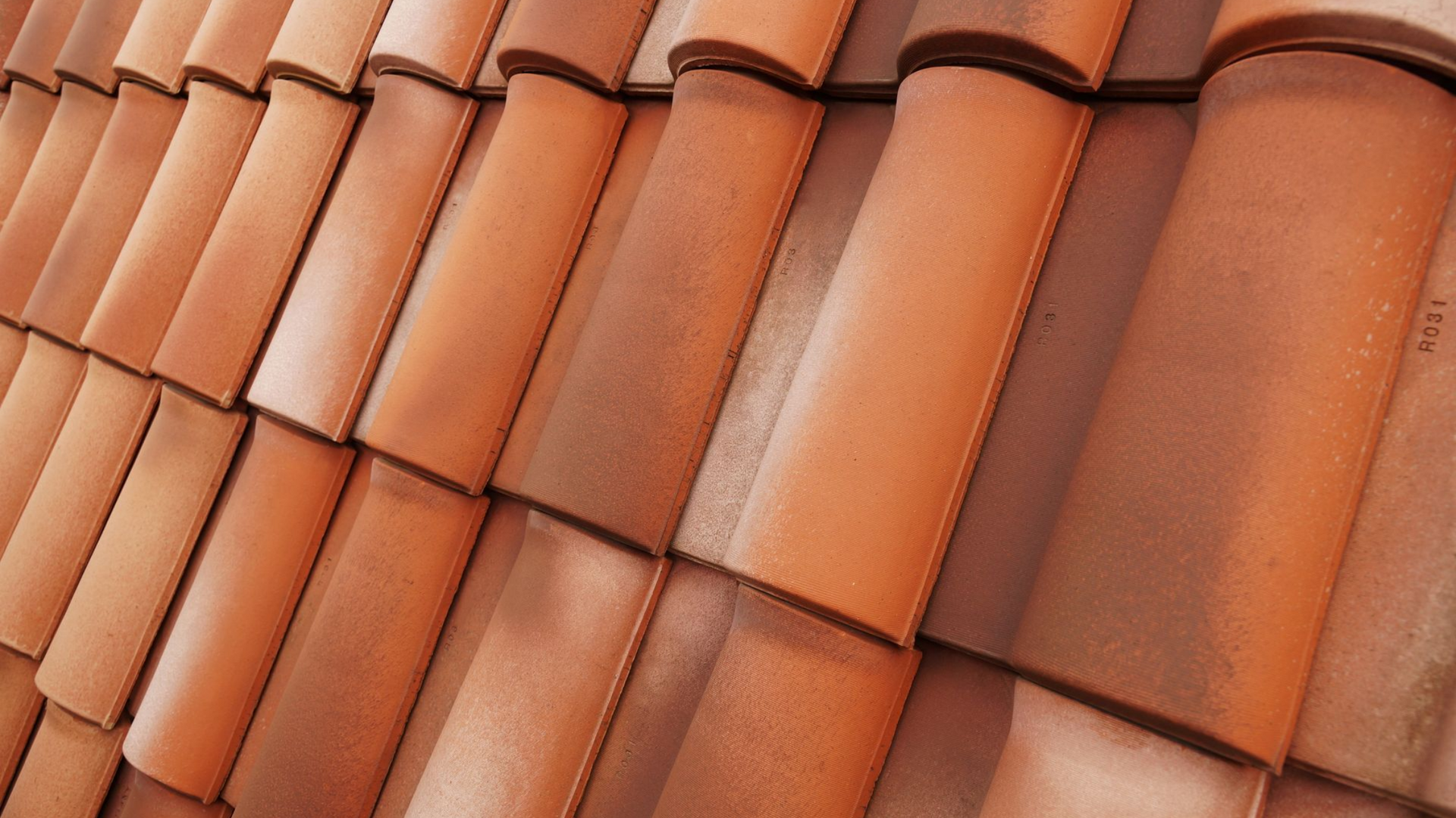 Tuiles de toit en terre cuite orange se chevauchant selon un motif diagonal