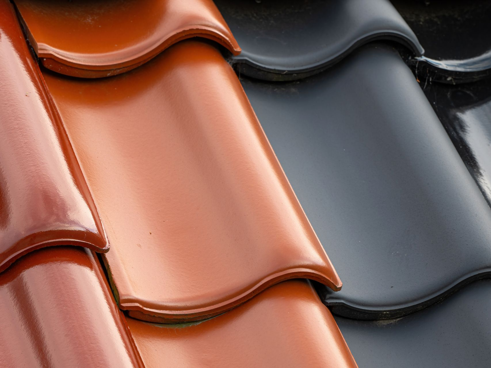 Gros plan sur des tuiles de toit brillantes qui se chevauchent, de couleur orange, grise et noire