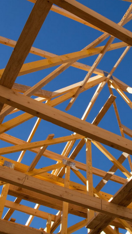 Charpente de toit en bois se détachant sur un ciel bleu clair sur un chantier de construction