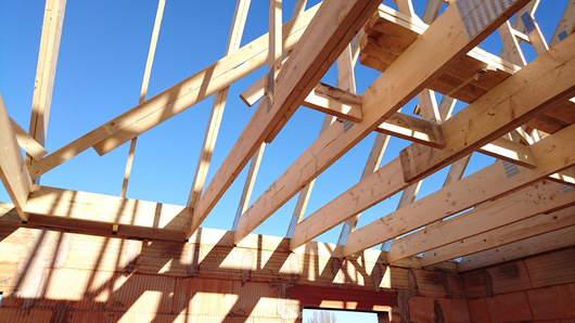 Charpente de toit en bois en construction, sur fond de ciel bleu éclatant