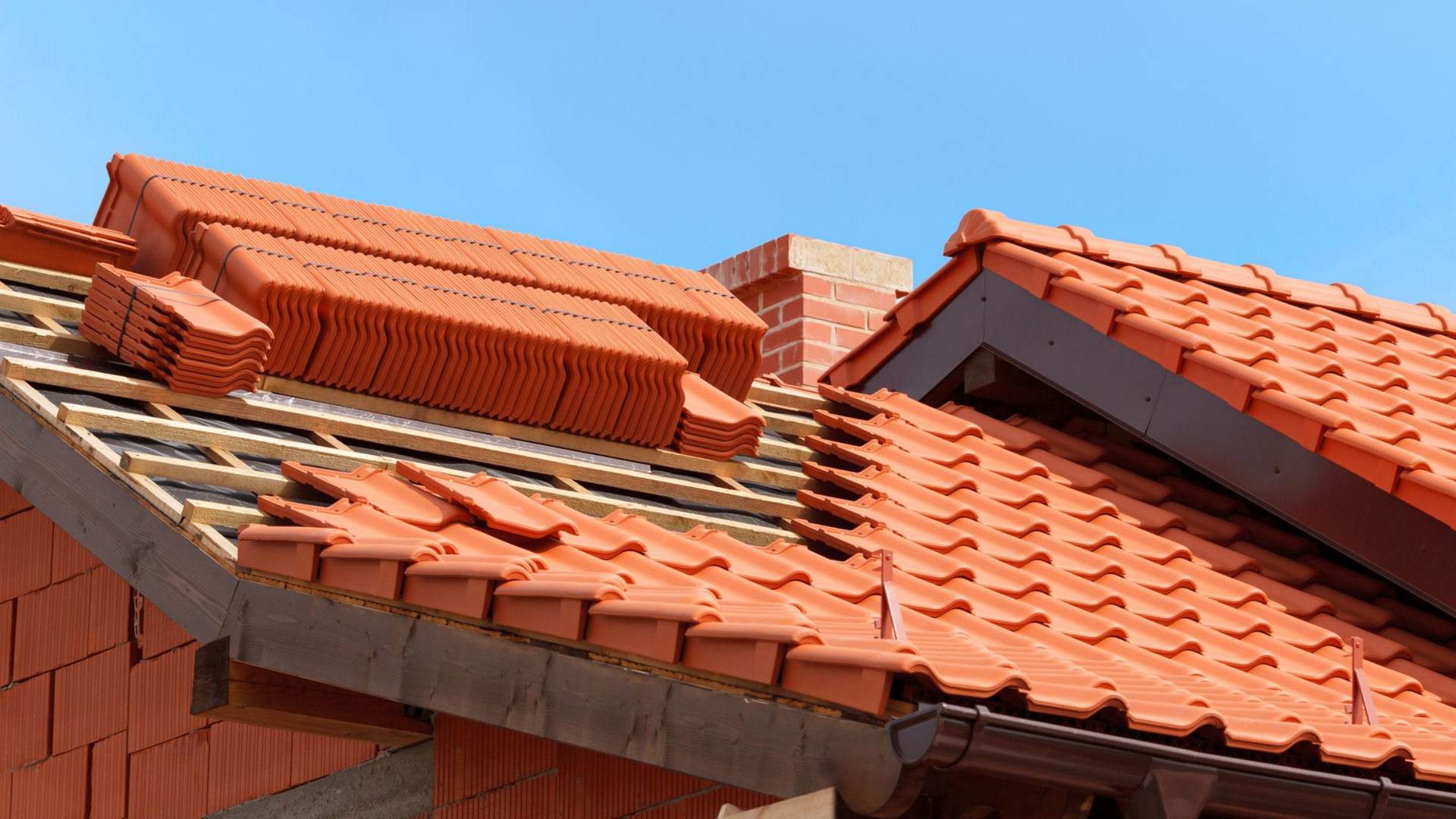 Tuiles de terre cuite rouge et lucarnes sur une maison sous un ciel bleu azur