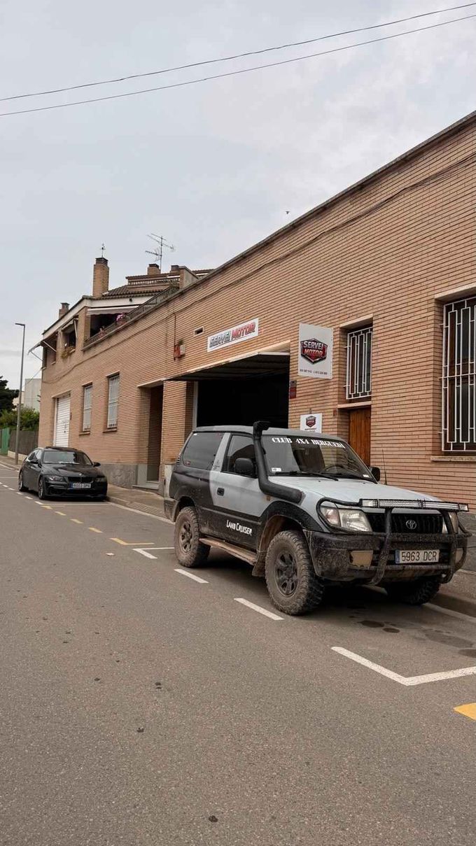Un todoterreno aparcado junto a un edificio de ladrillo en una calle tranquila bajo un cielo nublado.