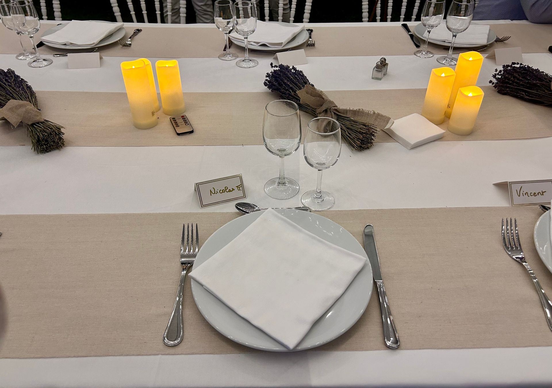 Table à manger dressée avec assiettes blanches, serviettes en lin et bougies.