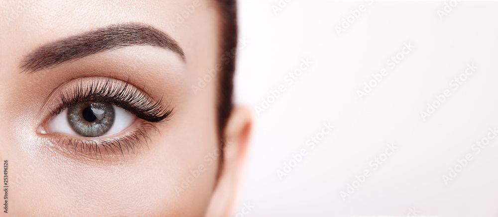 Nahaufnahme eines Auges mit gepflegten Augenbrauen, hellgoldenem Glitzerlidschatten und schwarzem Winged Eyeliner auf weissem Hintergrund.