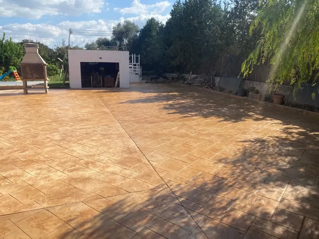 Un gran camino de entrada de hormigón con parrilla y garaje al fondo.