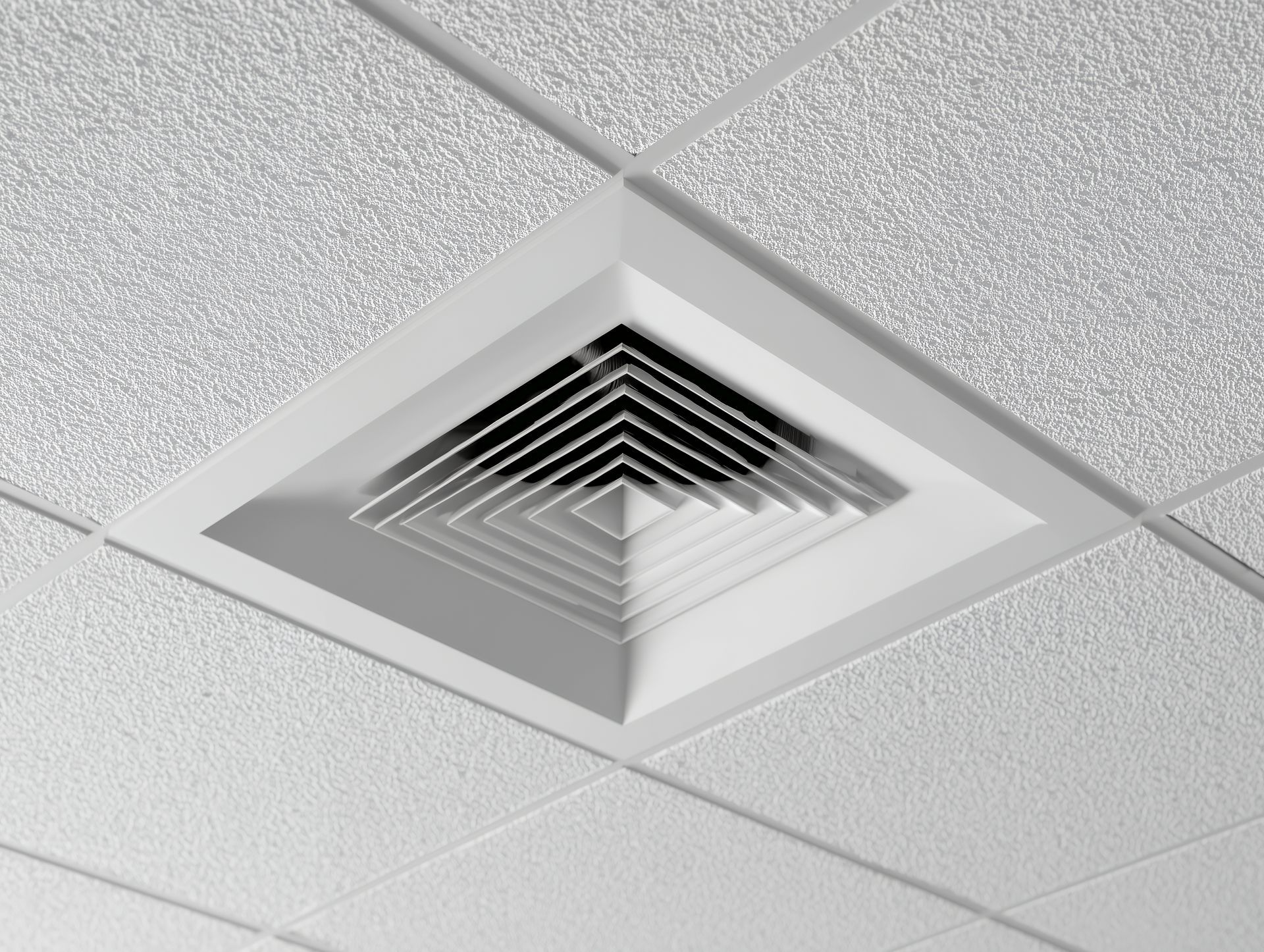 Grille d'aération de plafond dans un faux plafond blanc avec grille et cadre argentés
