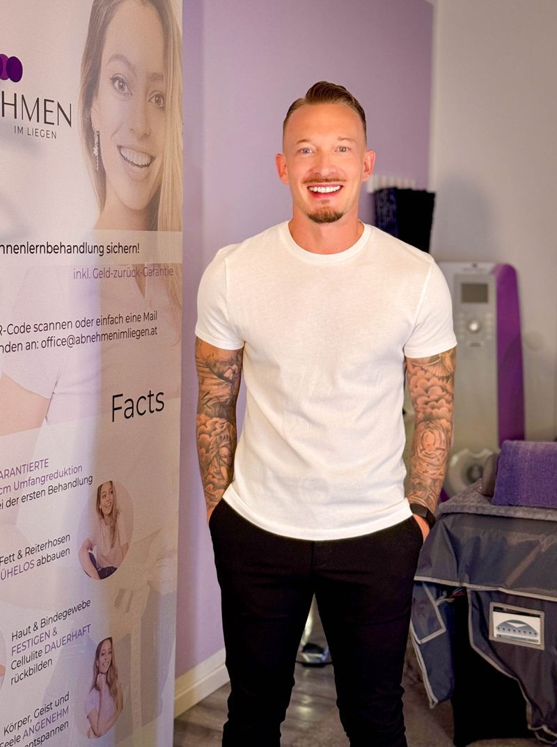 Ein Mann mit Bart lächelt und trägt ein blaues Hemd.