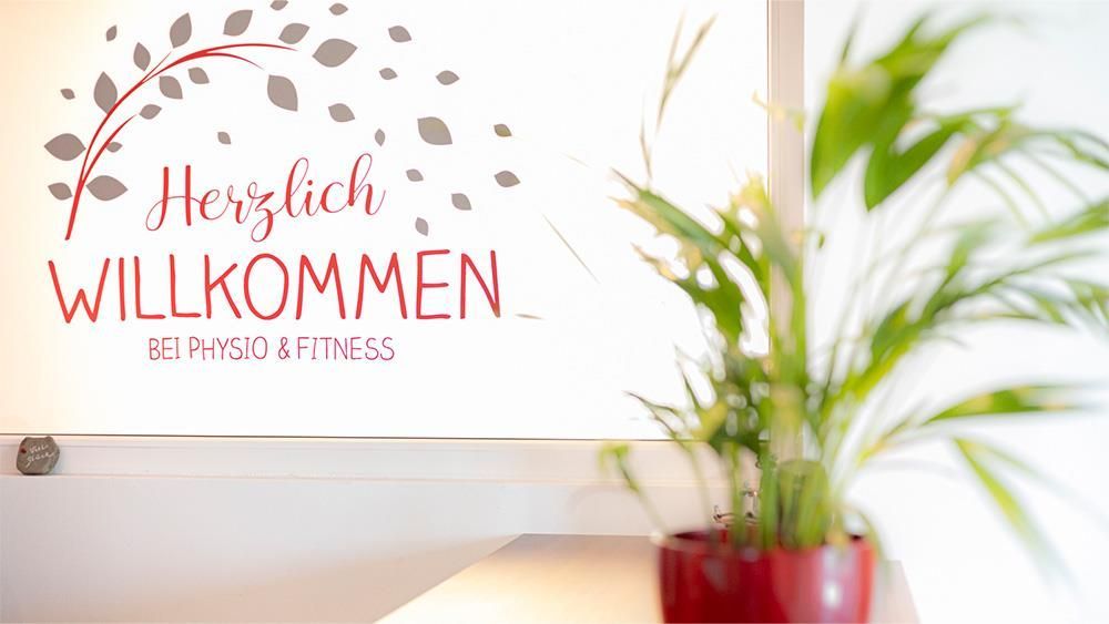 Eine Topfpflanze steht auf einem Tisch vor einem Schild mit der Aufschrift „Herzlich willkommen“.