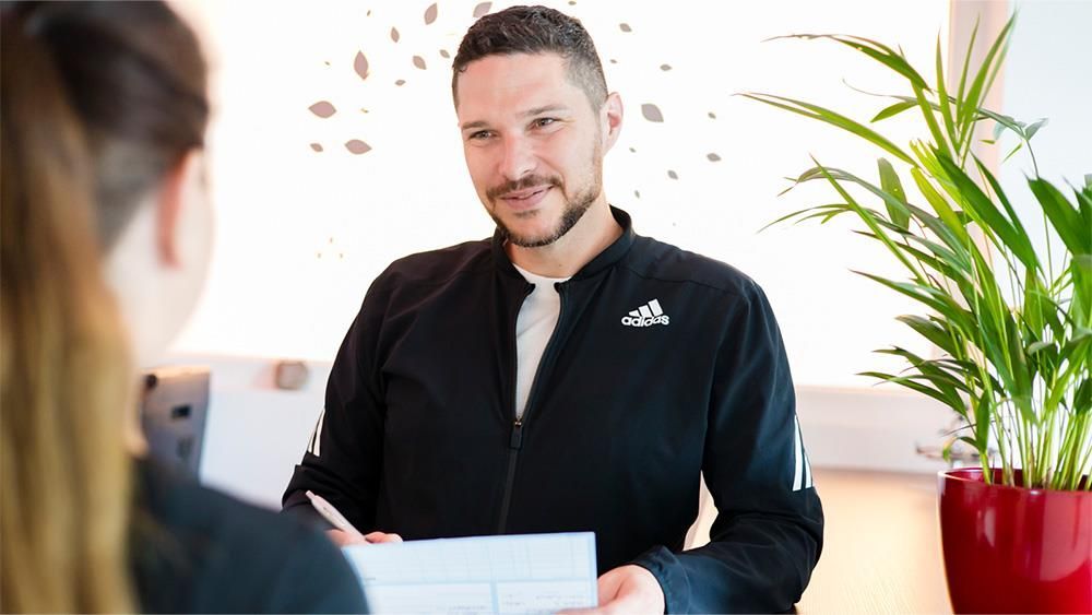 Ein Mann hält einer Frau ein Stück Papier vor die Nase.