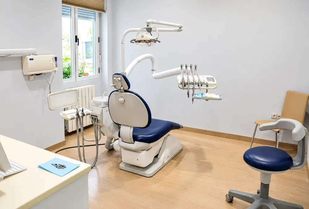 Clínica dental vacía con sillón, lámpara cenital y equipo de exploración en una sala luminosa