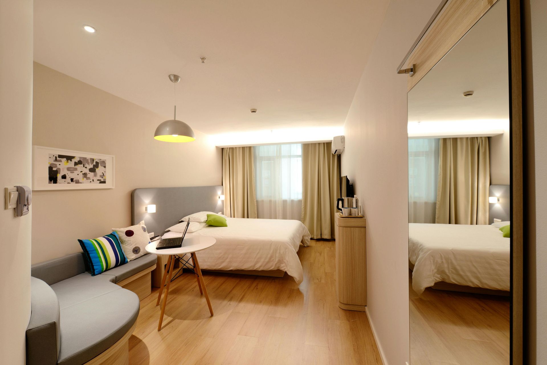Una habitación de hotel con dos camas, un sofá, una mesa y un espejo.