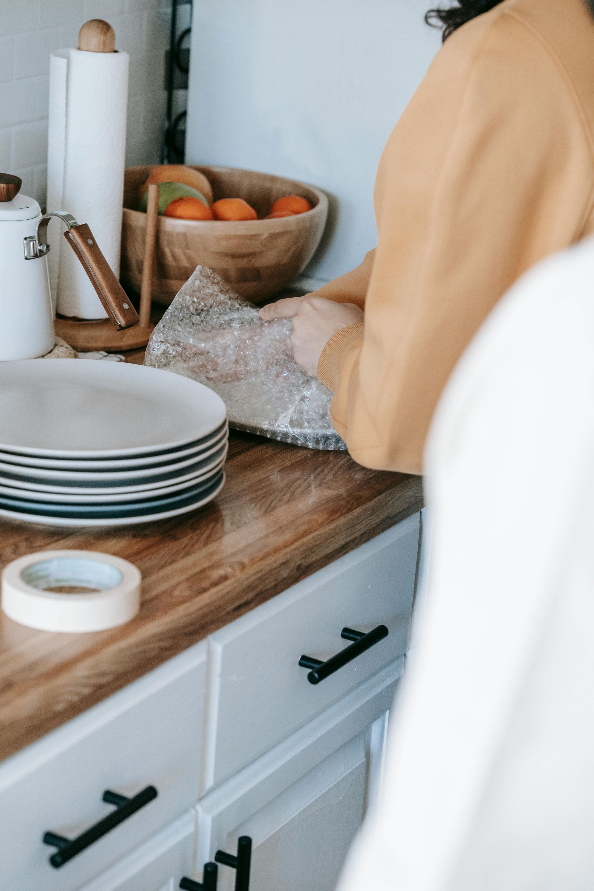 Una mujer envuelve platos en film plástico en una cocina.
