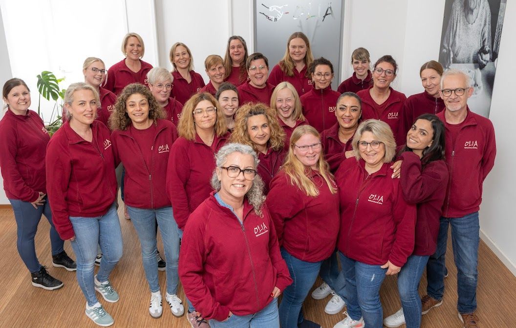 Mitarbeiter Olia: Eine große Gruppe von Menschen in roten Sweatshirts posiert für ein Foto.
