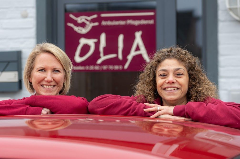 Mitarbeiterinnen Olia: Zwei Frauen lehnen auf dem Dach eines roten Olia Autos.
