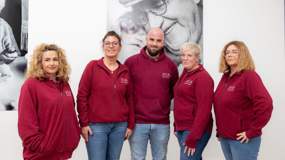Mitarbeiter Olia: Eine Gruppe von Menschen in kastanienbraunen Sweatshirts posiert für ein Foto.
