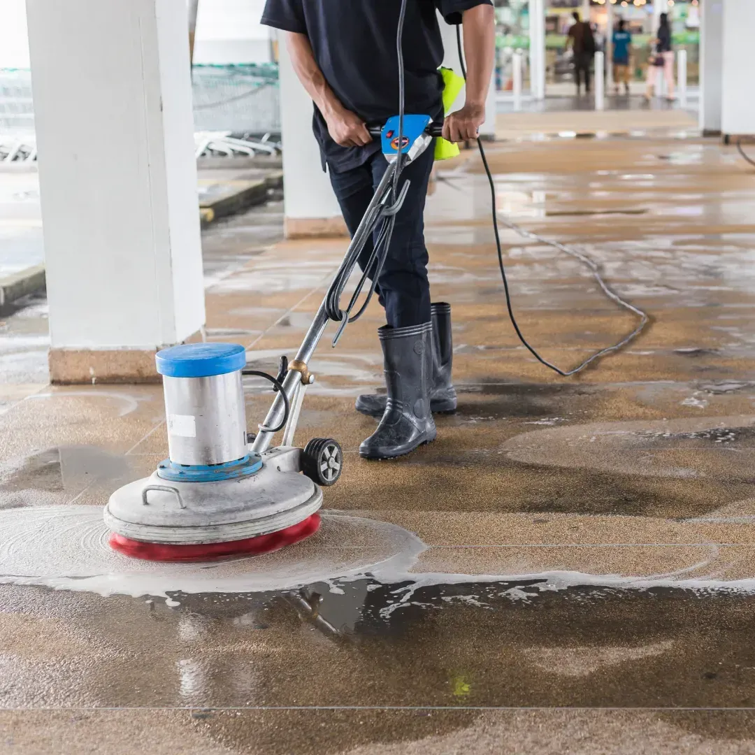 Un hombre está usando una máquina para limpiar un piso de concreto.