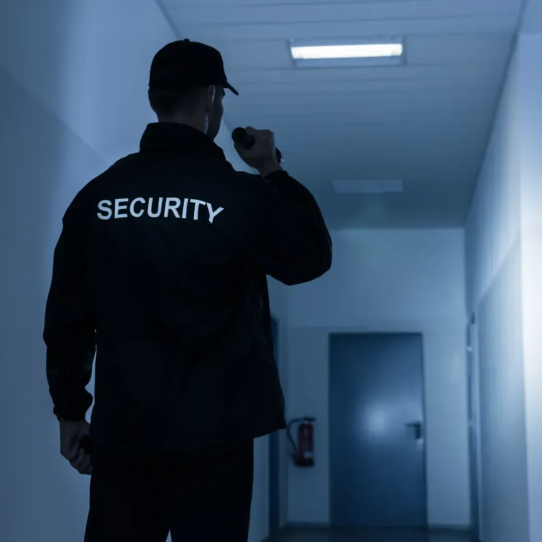 Un guardia de seguridad camina por un pasillo con una linterna.