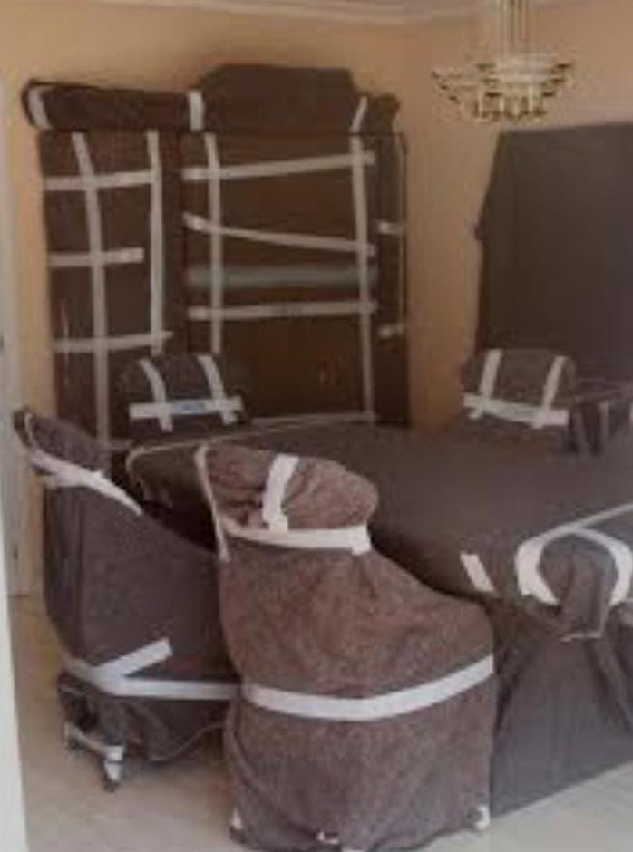 Una habitación llena de muebles envueltos en mantas y cinta adhesiva.