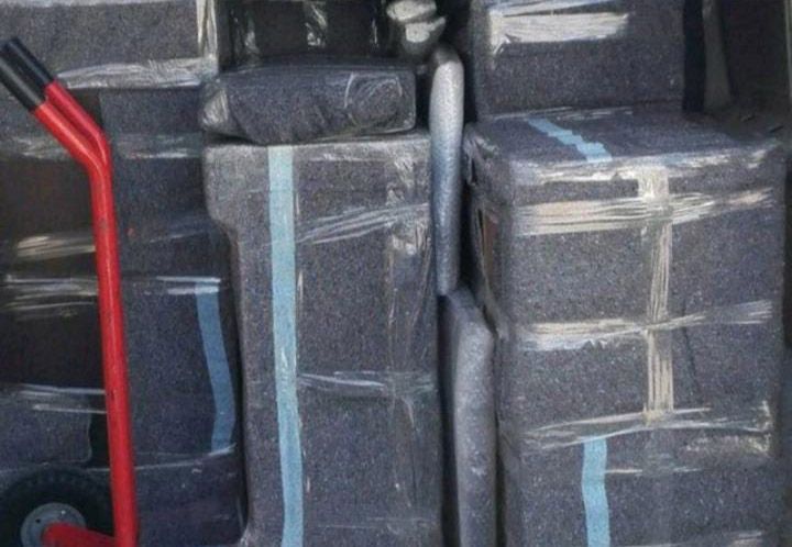 Una carretilla roja transporta una pila de cajas envueltas.