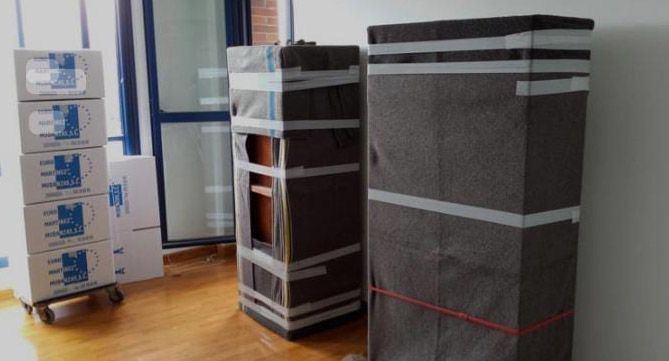 Una habitación llena de cajas y una cómoda envuelta en cinta adhesiva.