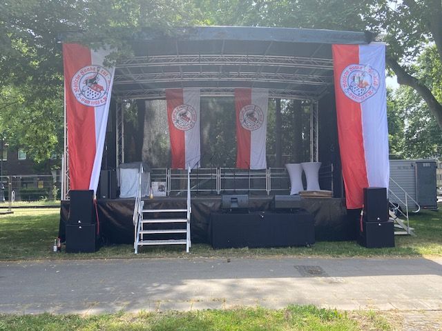 ein kleiner Anhänger mit einer Bühne darauf , die mit roten und weißen Fahnen geschmückt ist