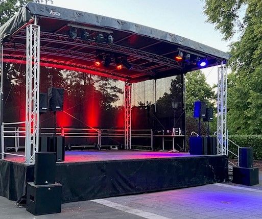 eine große , schwarze, geschlossene, mit roten und blauen Lichtern beleuchtete Konzertbühne