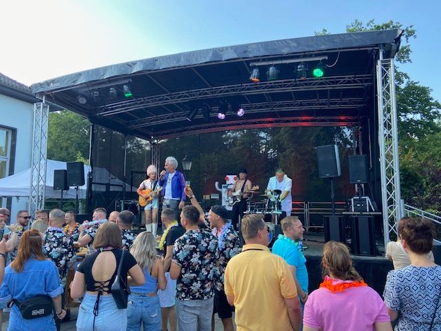 eine Gruppe von Menschen steht vor einer Bühne und schaut auf ein Konzert