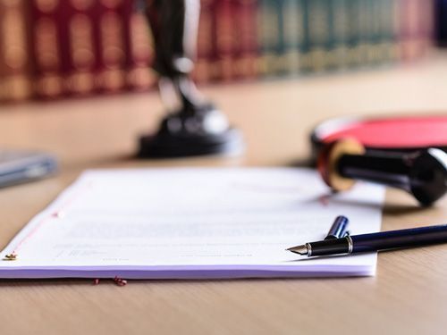 Un bolígrafo está encima de un trozo de papel sobre una mesa.