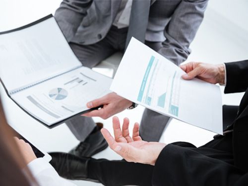 Un grupo de personas están sentadas alrededor de una mesa mirando papeles.