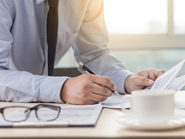 Un hombre está sentado en un escritorio escribiendo en un trozo de papel.