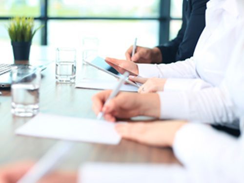 Un grupo de personas está sentada en una mesa escribiendo en papeles.