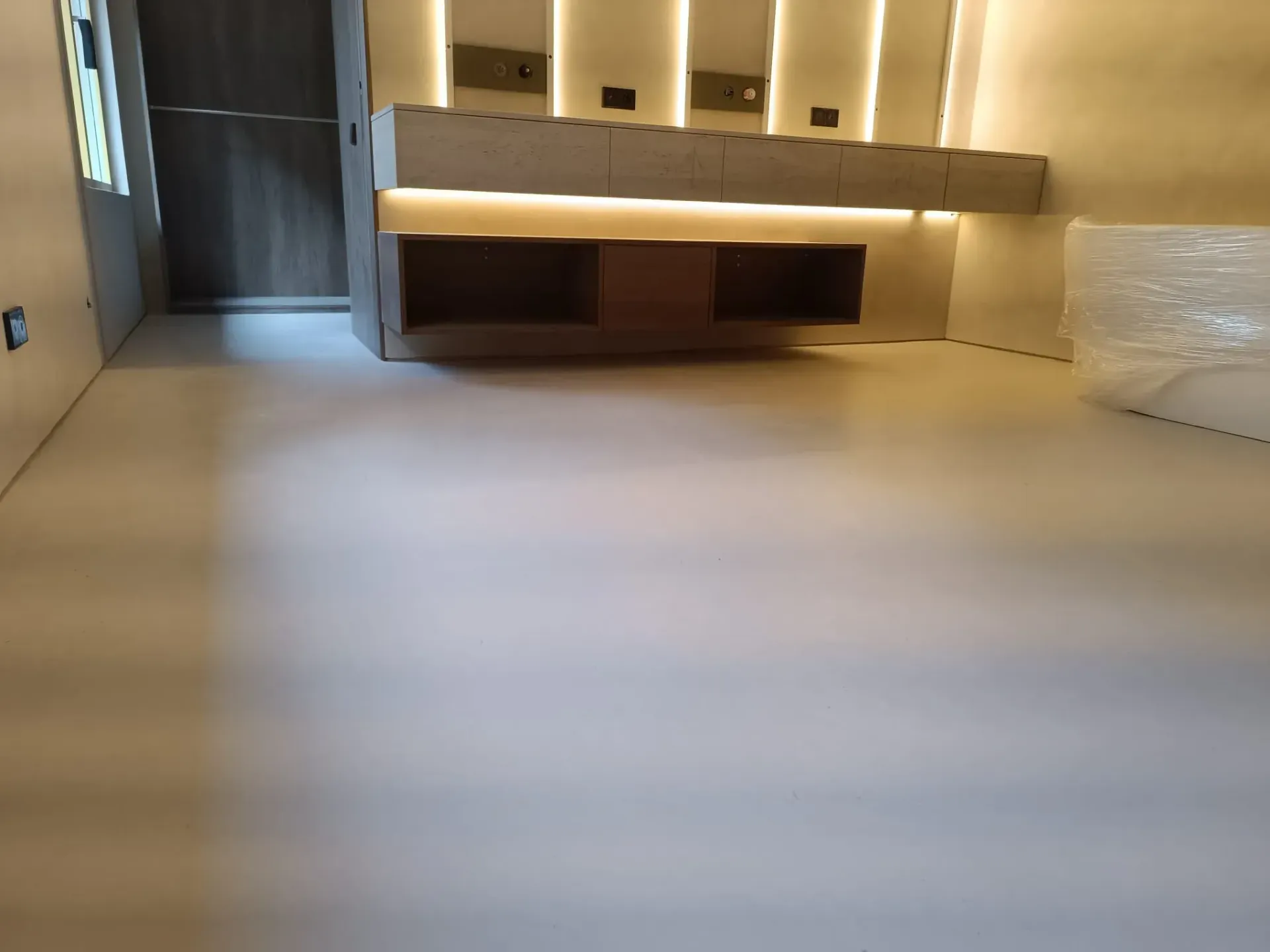 Habitación vacía con suelo de color claro, estantería empotrada e iluminación empotrada.