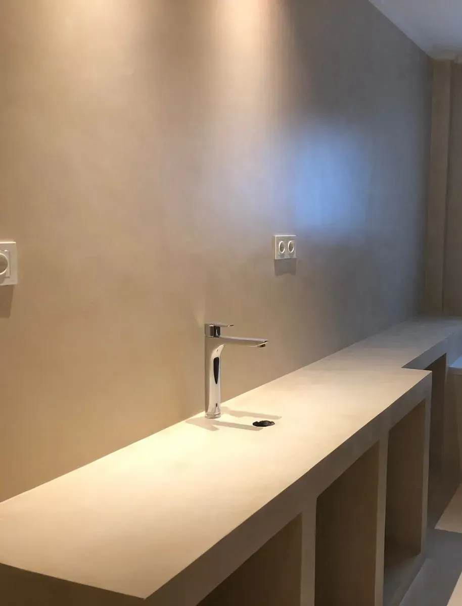 Cocina minimalista beige con fregadero y encimera empotrada. Enchufes visibles.