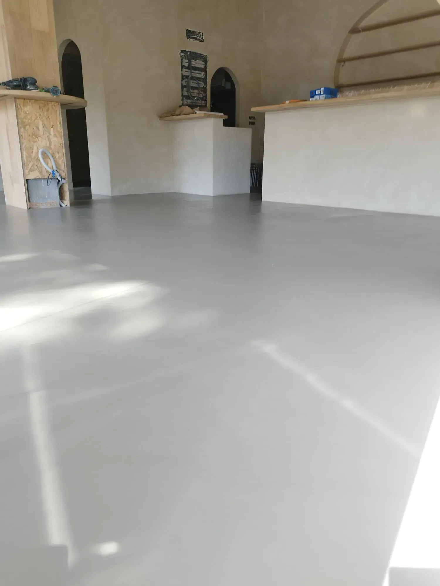 Piso de concreto gris, liso y pulido en el interior de una habitación con interior y encimeras de color claro.