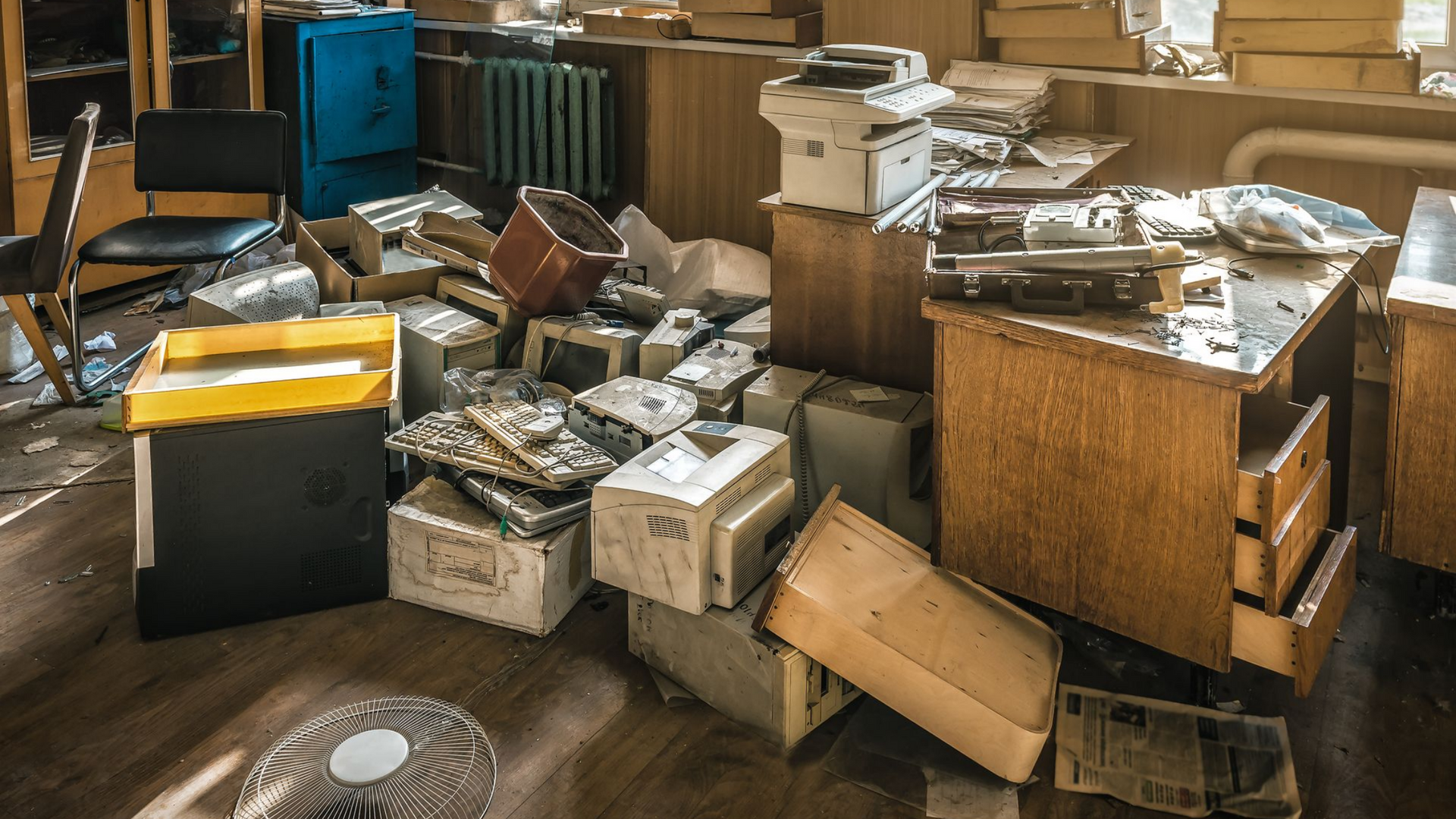 Bureau en désordre avec des boîtes éparpillées, un bureau, un copieur et une imprimante.