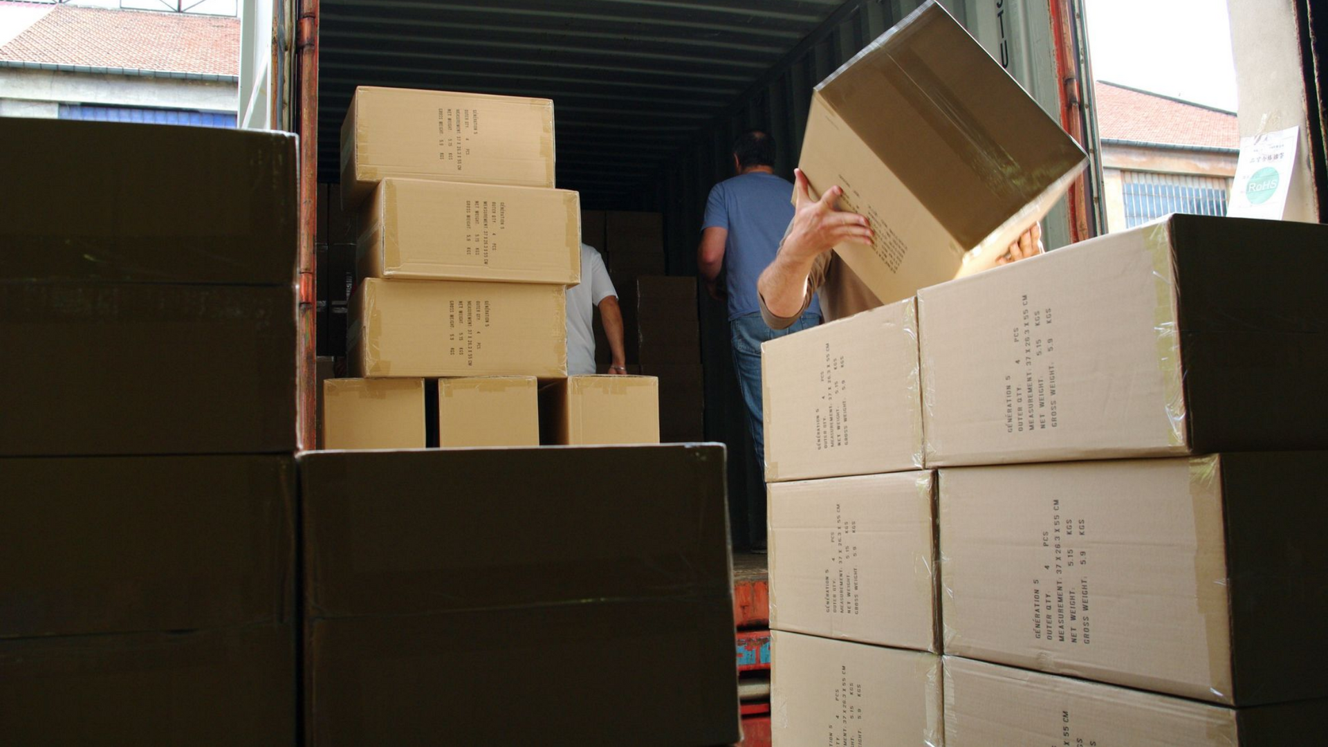 Des ouvriers chargent des cartons dans un conteneur d'expédition.