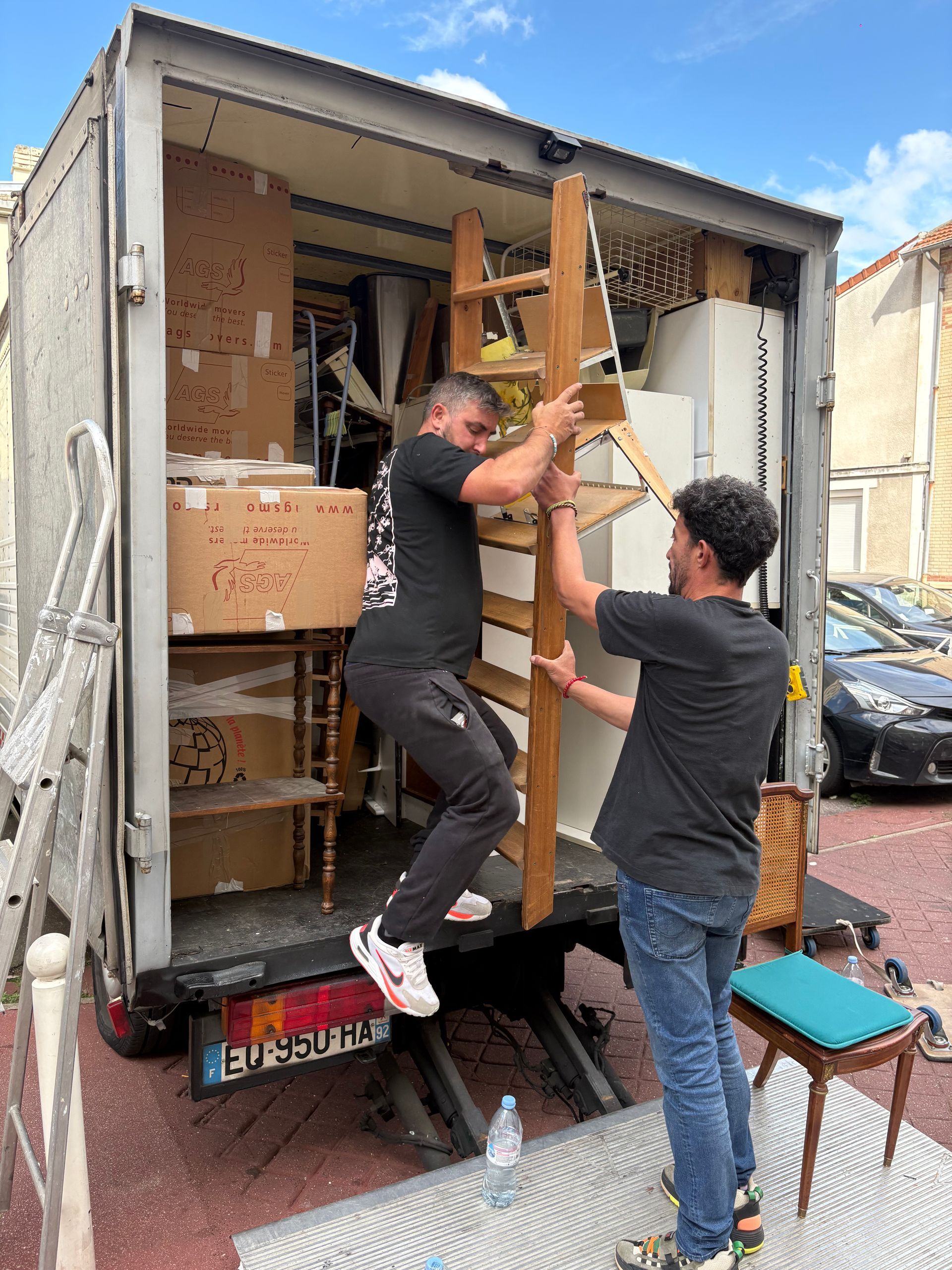 Deux hommes chargent des meubles dans un camion de déménagement.