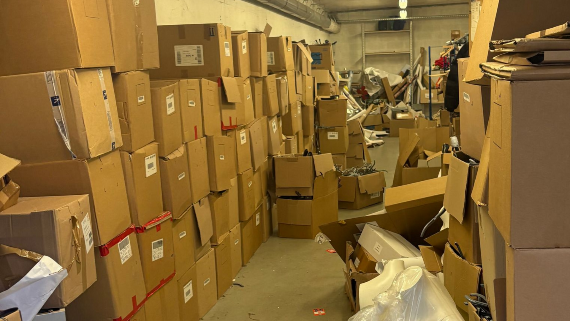 Intérieur d'entrepôt rempli de cartons empilés et de débris encombrés.