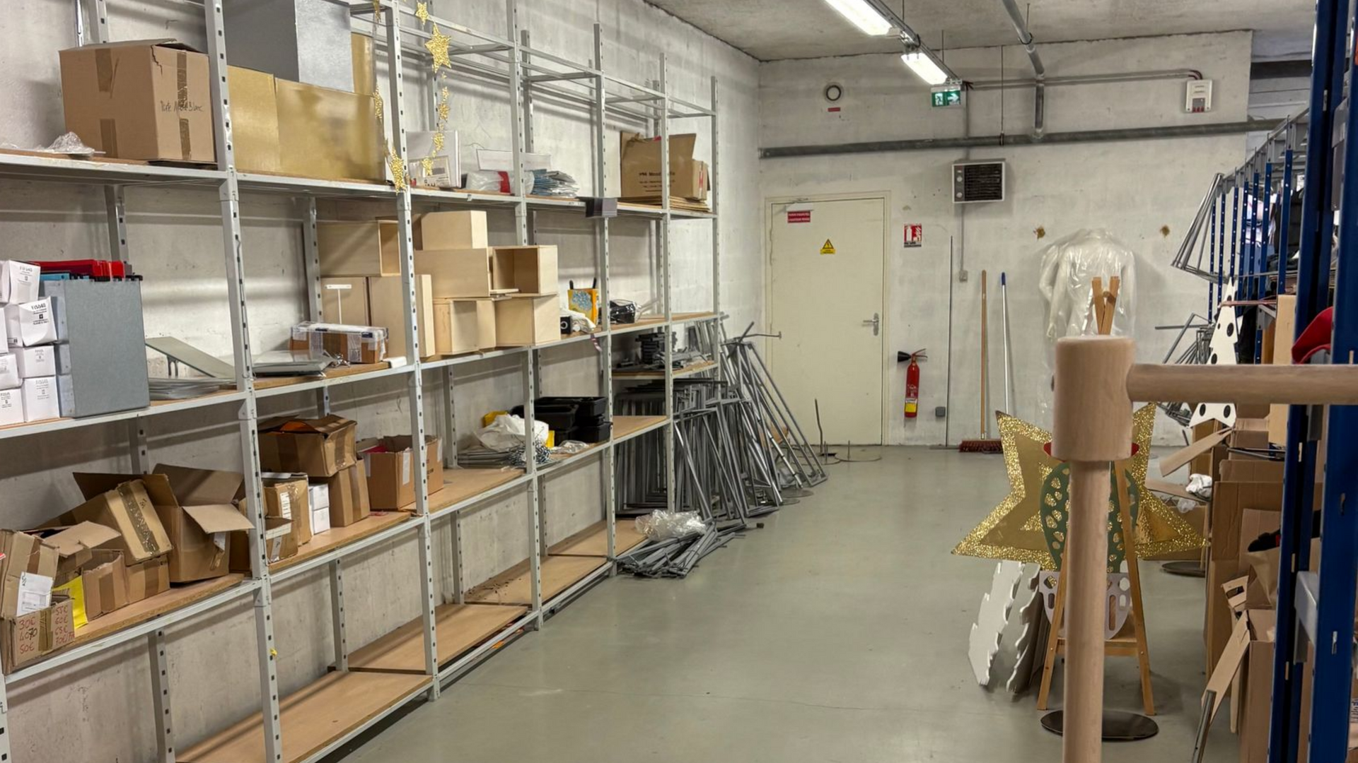 Intérieur d'entrepôt avec étagères métalliques remplies de boîtes et d'équipements.