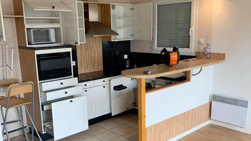 Petite cuisine avec armoires, four, micro-ondes et bar à déjeuner.