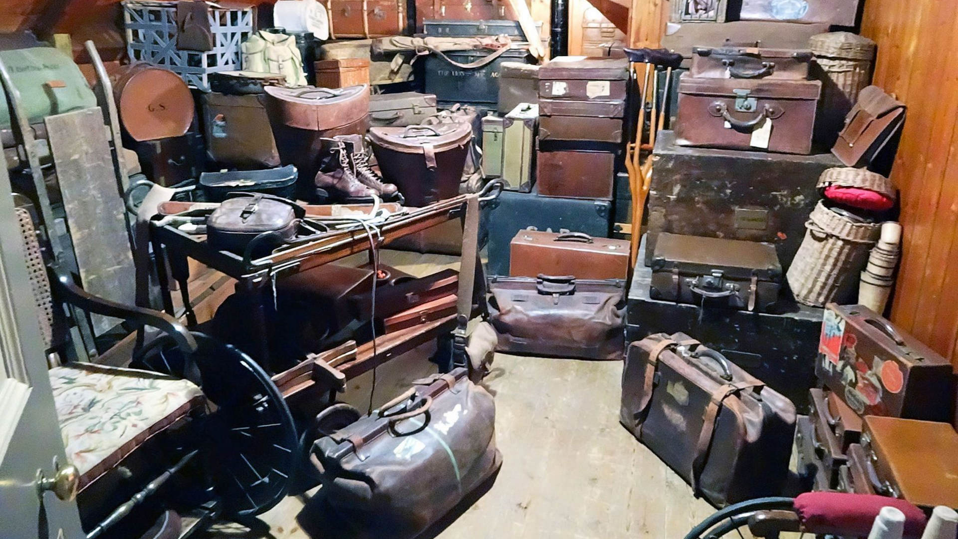 Une pièce encombrée remplie de nombreuses valises en cuir anciennes, de malles et de bagages vintage.