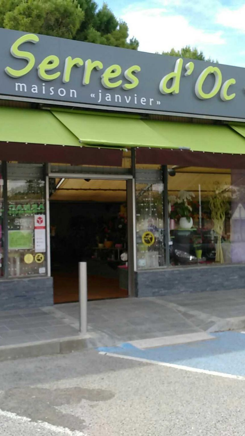 Devanture de magasin avec auvent vert, avec l'inscription de l'enseigne Les Serres d'Oc et entrée ouverte.
