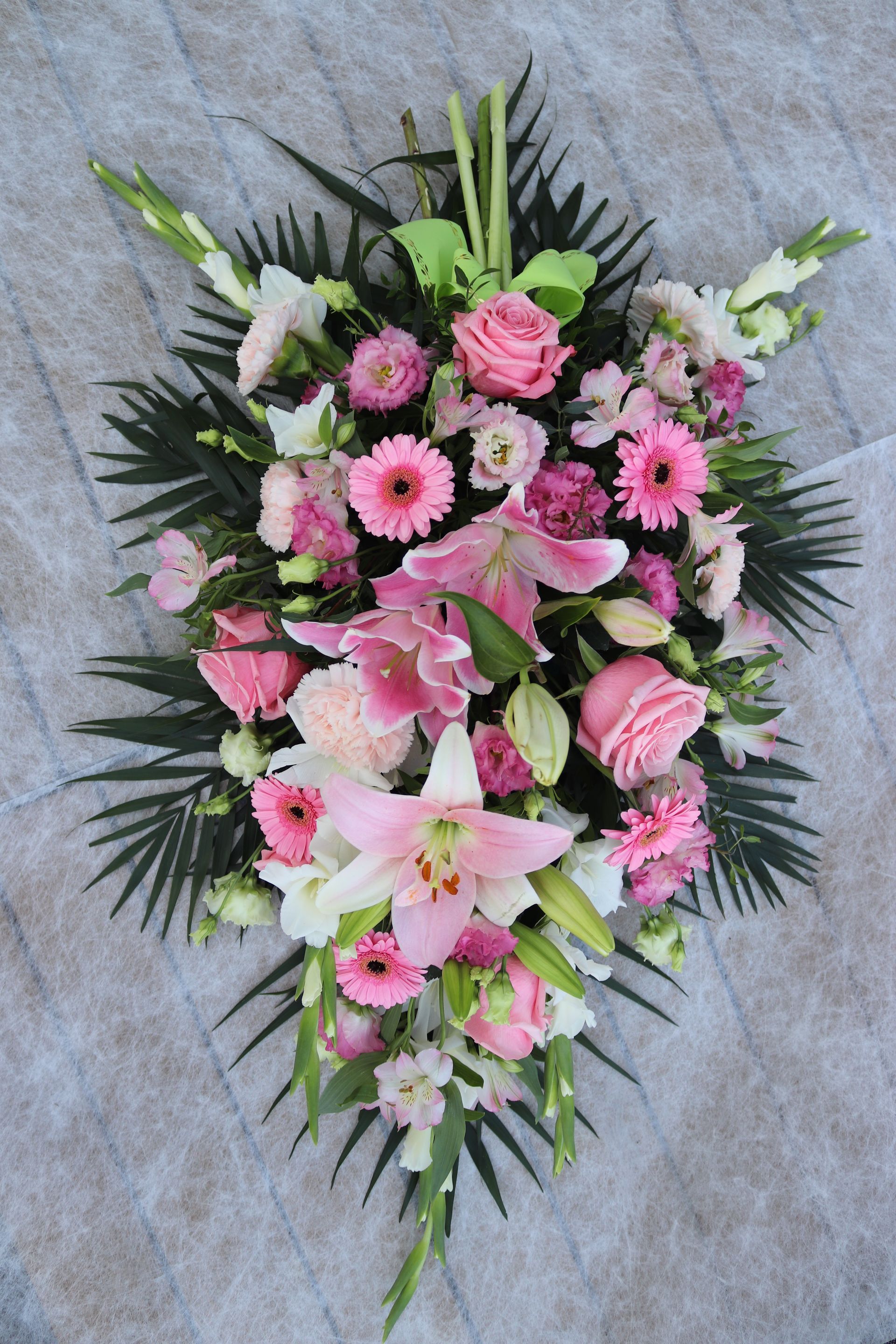 Pierre tombale ornée d'une statue d'ange et d'un arrangement floral en forme de cœur.
