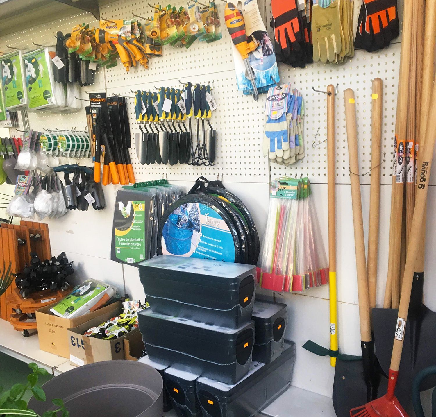 Outils et fournitures de jardinage exposés dans un magasin : pelles, gants et jardinières.